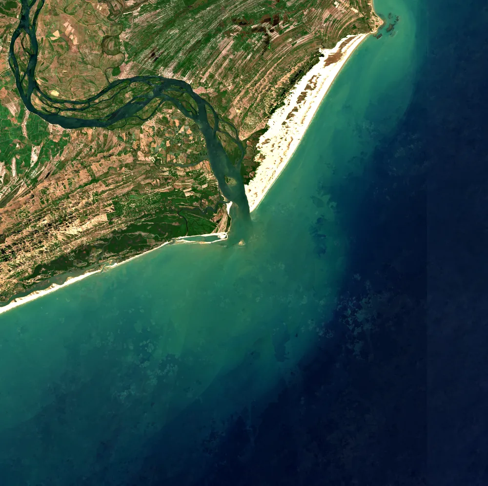 Composição Sentinel-2 em cor verdadeira da foz do rio São Francisco: o rio desce do noroeste, a pluma de sedimentos entra no oceano e as dunas claras do Pontal do Peba acompanham a costa