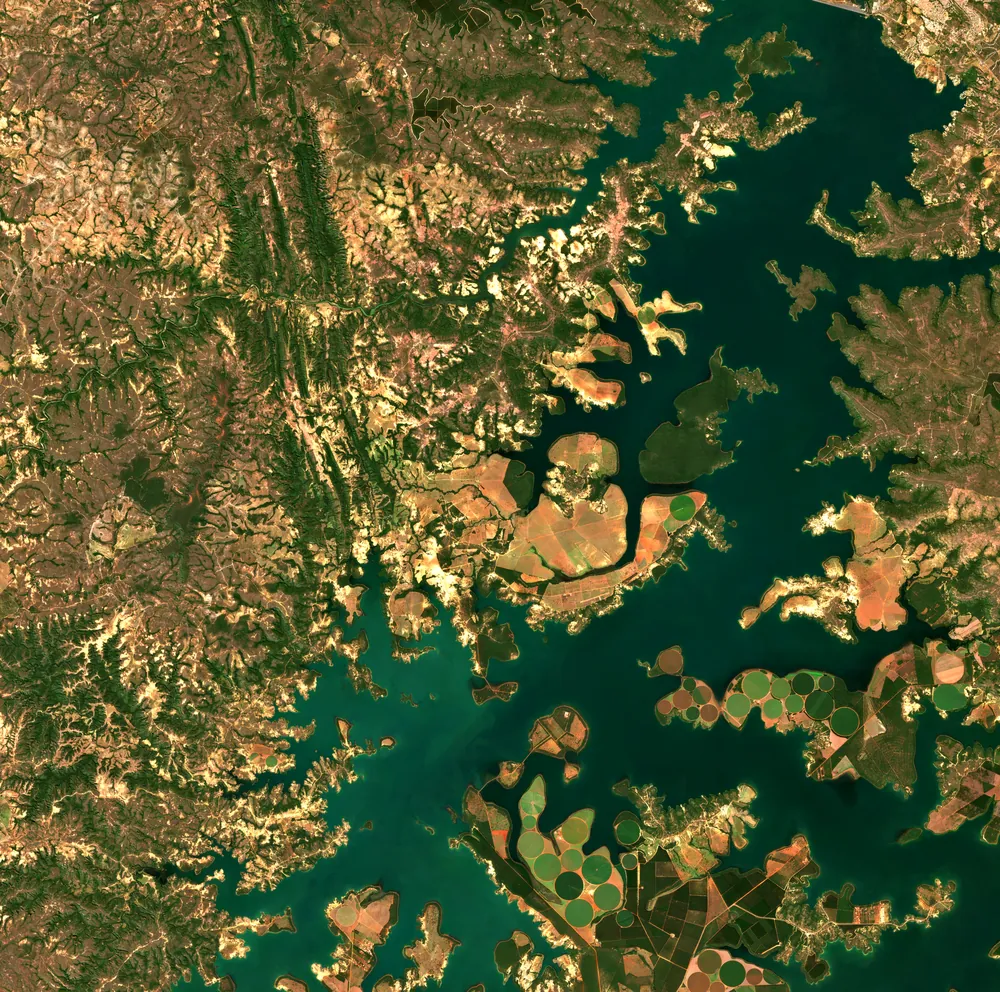 Composição Sentinel-2 em cor verdadeira do reservatório de Três Marias: a água escura em braços dendríticos, círculos de pivôs de irrigação e o cerrado seco em tons de marrom